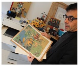 Olivier Schwartz tenant l'illustration dans ses mains, dans son atelier