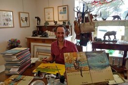 Benjamin Flao en train de dédicacer avec la planche en arrière plan